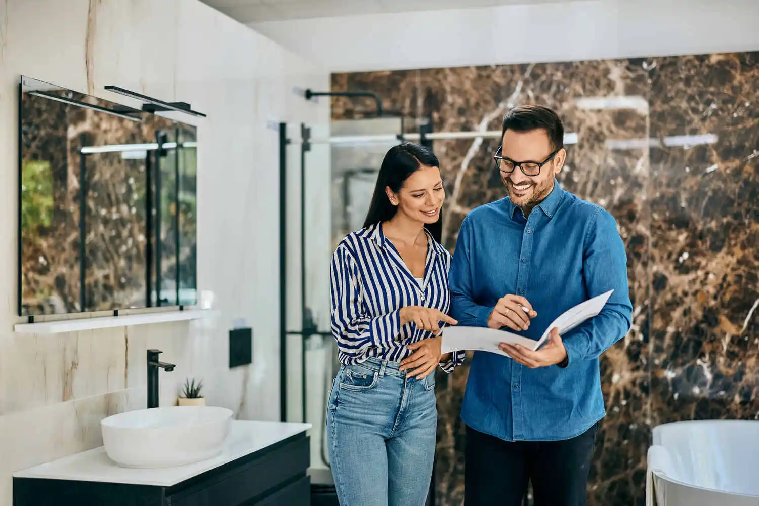 They are surrounded by bathroom fixtures and tile samples, with various sinks and bathtubs visible.